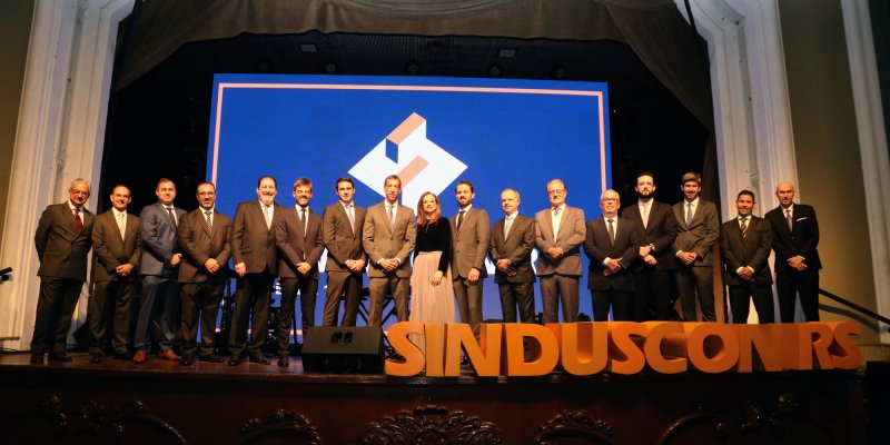 Homens e mulheres enfileirados em cima de um palco - aos pés escrito Sinduscon-RS